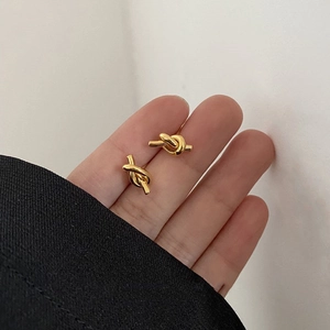 Minimalist knot design gold plated stud earrings held in hand for a stylish jewelry look