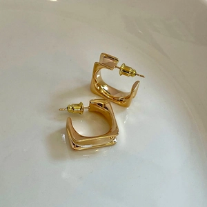 Detailansicht goldener minimalistischer quadratischer Creolen mit Hochglanzoberfläche