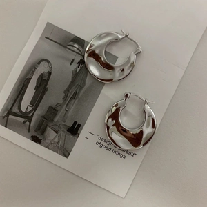 Detail von silbernen Creolen mit unregelmäßiger Hammerschlag-Textur und Liquid-Metal-Finish