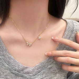 Collier doré élégant avec pendentifs nœud et fleurs en zircone sur décolleté avec haut gris