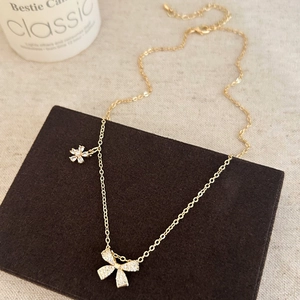 Détail du collier noeud doré avec oxydes de zirconium et petit pendentif fleur chic