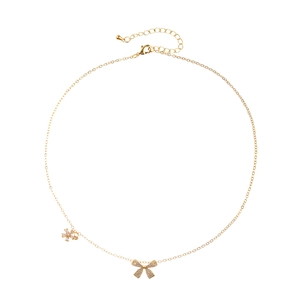Collier doré avec pendentifs nœud en zircone et flocon de neige sur fond blanc