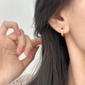 Orecchini a cerchio dorati ondulati con zirconi indossati da una modella