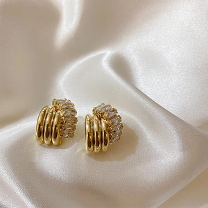 Detailed view of layered gold-tone zircon earrings on soft satin background