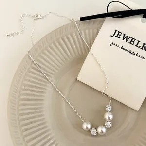 Macro detail of French vintage pearl necklace with pavé crystal balls on a beige tray