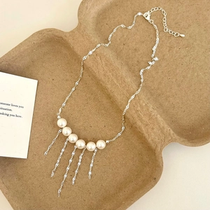 Close-up of pearl fringe necklace with silver chain on minimalist background