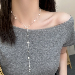 Elegant Y-shaped silver chain necklace with transparent glass beads worn by a model