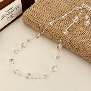 Elegant beaded necklace with clear glass beads and silver chain on textured background