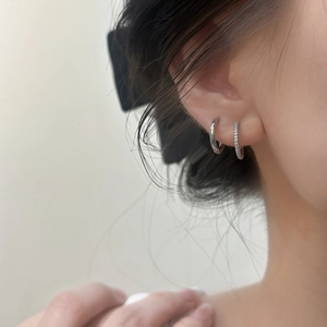 Créoles minimalistes en argent avec zircons portées par un mannequin pour un look chic
