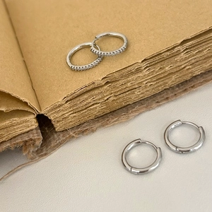 Détail de créoles en argent poli et boucles d'oreilles serties de zircons sur un vieux livre
