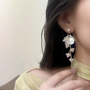 Detail of elegant floral tassel earrings with pearls and crystals on a model