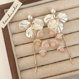 Detail of floral petal tassel earrings with pearls and gold chains in a jewelry box