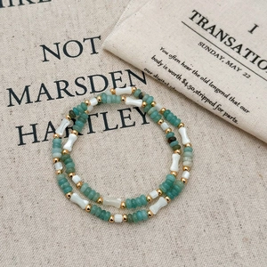Détail d'un collier de perles vertes rondes, perles blanches en os et accents dorés élégants