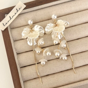 Macro shot of pearl flower tassel earrings on a luxury velvet jewelry display tray