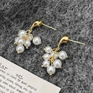 Vue macro de boucles d'oreilles élégantes en grappe de perles sur un fond en tissu texturé