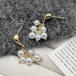 Boucles d'oreilles élégantes en grappe de perles dorées sur fond de tissu texturé haut de gamme