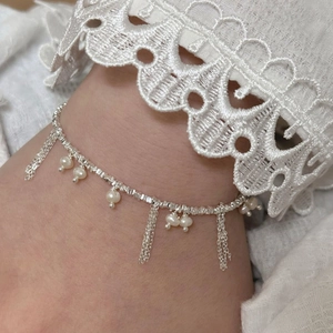 Elegant silver ankle bracelet with hanging white pearls and fine tassels worn on a foot
