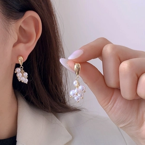 Boucles d'oreilles élégantes en grappe de perles dorées portées par un mannequin chic