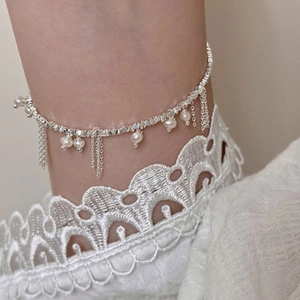 Silver tassel ankle bracelet with white pearls shown on ankle with lace background
