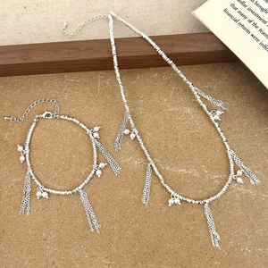 Detailed view of silver necklace and bracelet set with pearl accents and fringe tassels