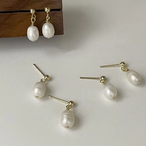Detailed view of baroque freshwater pearls on gold-plated minimalist stud earrings