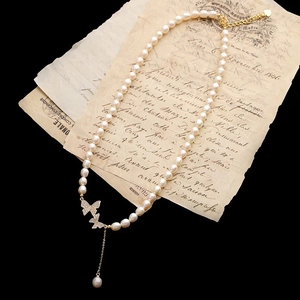 Détail d'un collier de perles naturelles avec breloques papillons sur papier vintage