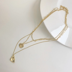 Layered gold-plated necklace with triple chains and irregular hammered pendants