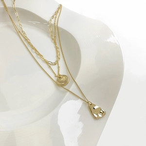 Three-layer gold plated layered necklace with sunburst coin and molten lava shield pendant