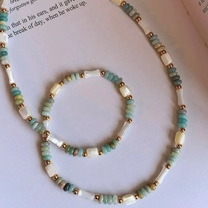 Ensemble collier et bracelet en perles de nacre et bambou sur un livre ouvert