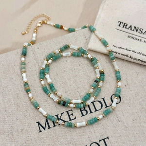 Ensemble de bijoux avec perles vertes et éléments en coquillage sur tissu texturé