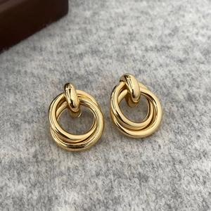 Elegant geometric interlocking gold hoop earrings on a textured minimalist background