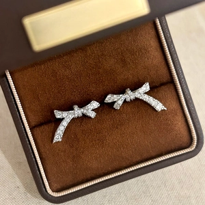Boucles d'oreilles nœud argentées avec zircons dans une boîte à bijoux