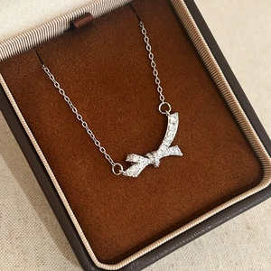 Gros plan d'un collier nœud argenté avec zircons étincelants dans un coffret à bijoux en velours
