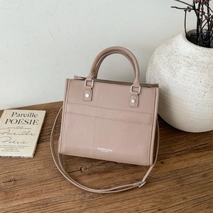 Borsa tote beige a grana di litchi con manici superiori e tracolla regolabile su legno