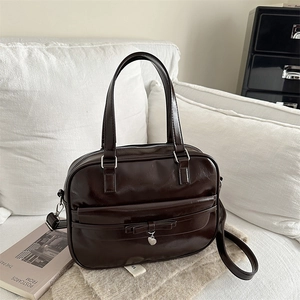 Deep brown large capacity tote bag with bow and heart pendant on a white sofa