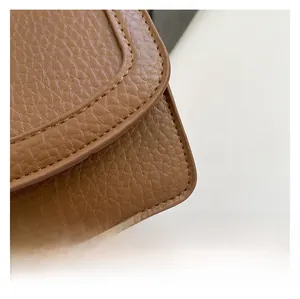 Close-up of caramel brown lychee leather texture and precise stitching on the handbag