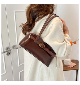 Detailansicht der dunkelbraunen Lackleder-Baguette-Tasche kombiniert mit weißem Mantel