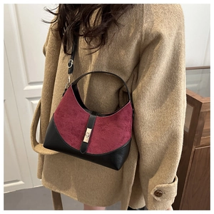 Detail of burgundy suede and black leather bucket bag with gold metallic buckle and strap