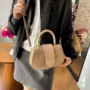 Detail of beige crossbody bag featuring woven texture flap and gold U-shaped hardware