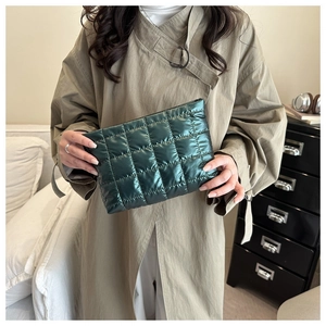Detail of dark green quilted clutch bag in glossy nylon fabric with square stitching