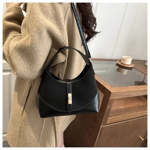 Detail of black suede and leather bucket bag featuring a gold metal lock and shoulder strap