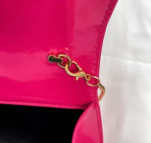 Detailed close-up of the elegant rose red patent leather and gold chain metal clasp