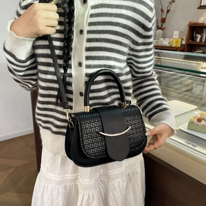 Lifestyle view of black square handbag with crocodile texture and gold hardware