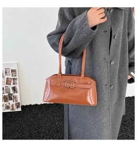 Detail einer braunen glänzenden PU-Lederhandtasche mit dekorativer goldener Metallschnalle