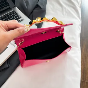 Detailed view of magenta patent leather bag with gold wave handle and magnetic closure