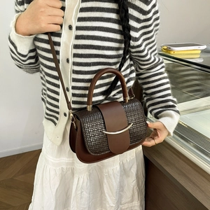 Détail d'un sac à main marron avec rabat tressé et fermoir métallique doré chic