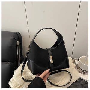 Detail of black bucket bag featuring suede and leather textures with a golden metal twist lock