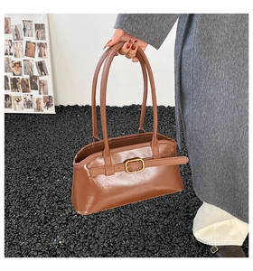 Detail einer braunen Vintage-Lederhandtasche mit Glanzeffekt und goldener Metallschnalle
