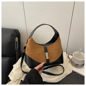 Detail of two-tone bucket bag with brown suede and black leather finish with gold clasp