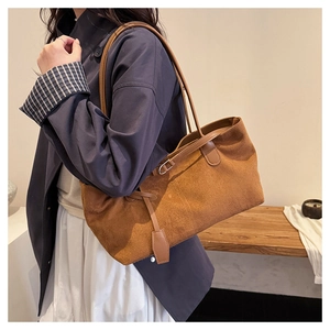 Gros plan du cabas en daim caramel avec bandoulière en cuir porté par un mannequin chic